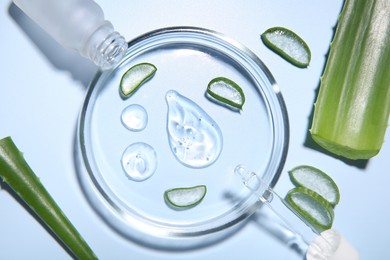 Photo of Cut aloe vera, bottle and drops of cosmetic gel on light blue background, flat lay