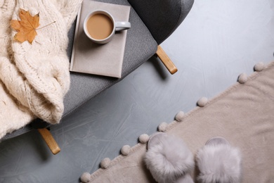 Warm sweater and book on armchair indoors, flat lay