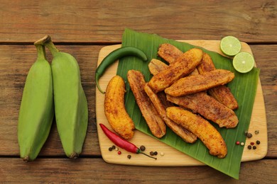 Photo of Delicious fried bananas, fresh fruits and different peppers on wooden table, flat lay