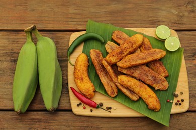 Delicious fried bananas, fresh fruits and different peppers on wooden table, flat lay