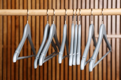 Empty hangers on rail against wooden background