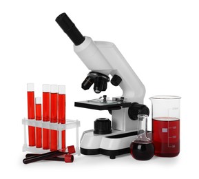 Photo of Laboratory glassware with red liquid and microscope isolated on white