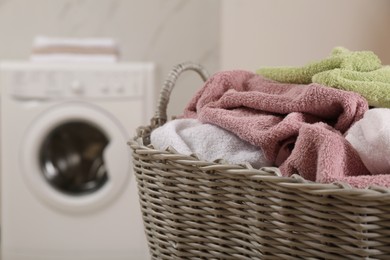 Photo of Wicker basket with dirty laundry in bathroom, closeup