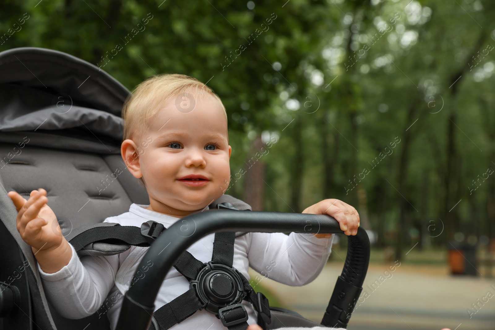 Photo of Cute little child in black stroller outdoors