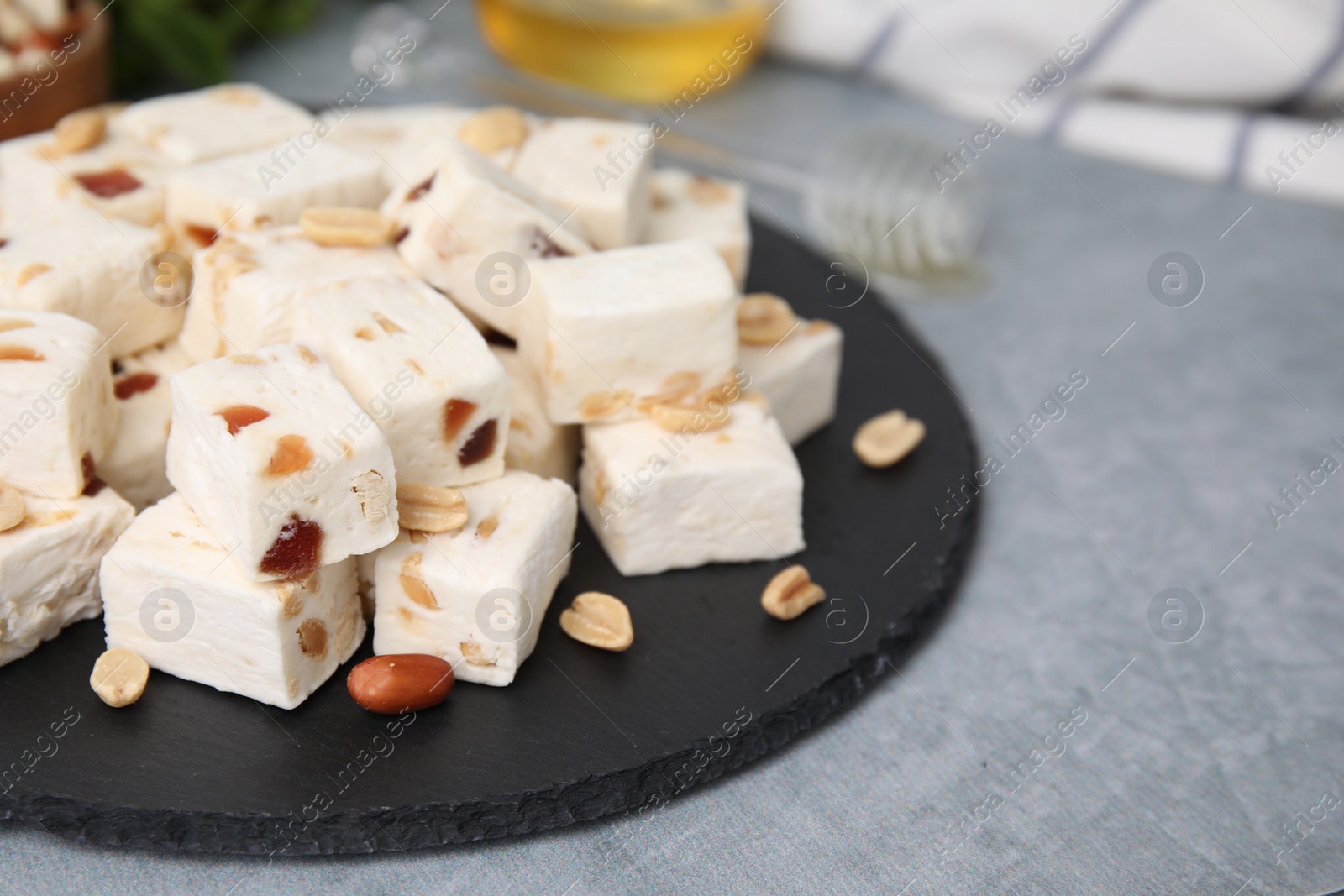 Photo of Pieces of delicious nutty nougat on grey table, closeup