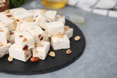 Pieces of delicious nutty nougat on grey table, closeup