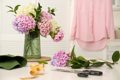 Photo of Bouquet of beautiful hydrangea flowers on white table indoors. Interior design