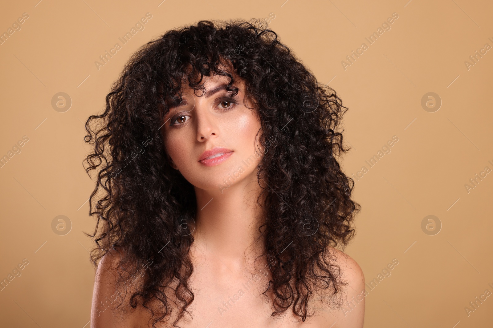 Photo of Beautiful young woman with long curly hair on beige background