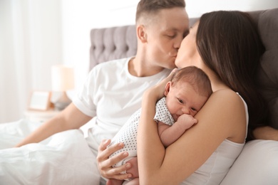 Photo of Happy couple with their newborn baby on bed