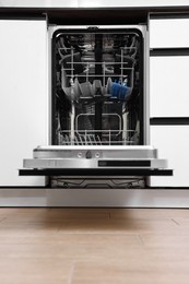Photo of Built-in dishwasher with open door indoors. Home appliance