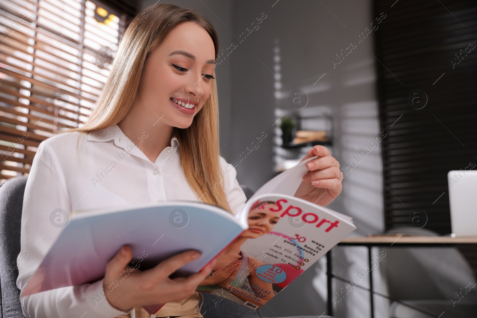 Photo of Happy woman reading interesting magazine in office