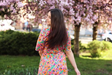 Beautiful woman near blossoming trees on spring day