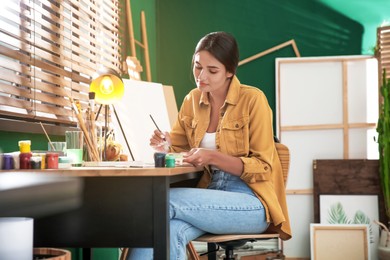 Photo of Young woman drawing on paper at table indoors