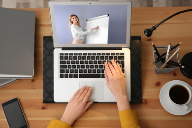 Woman having online video consultation with business trainer at table, top view