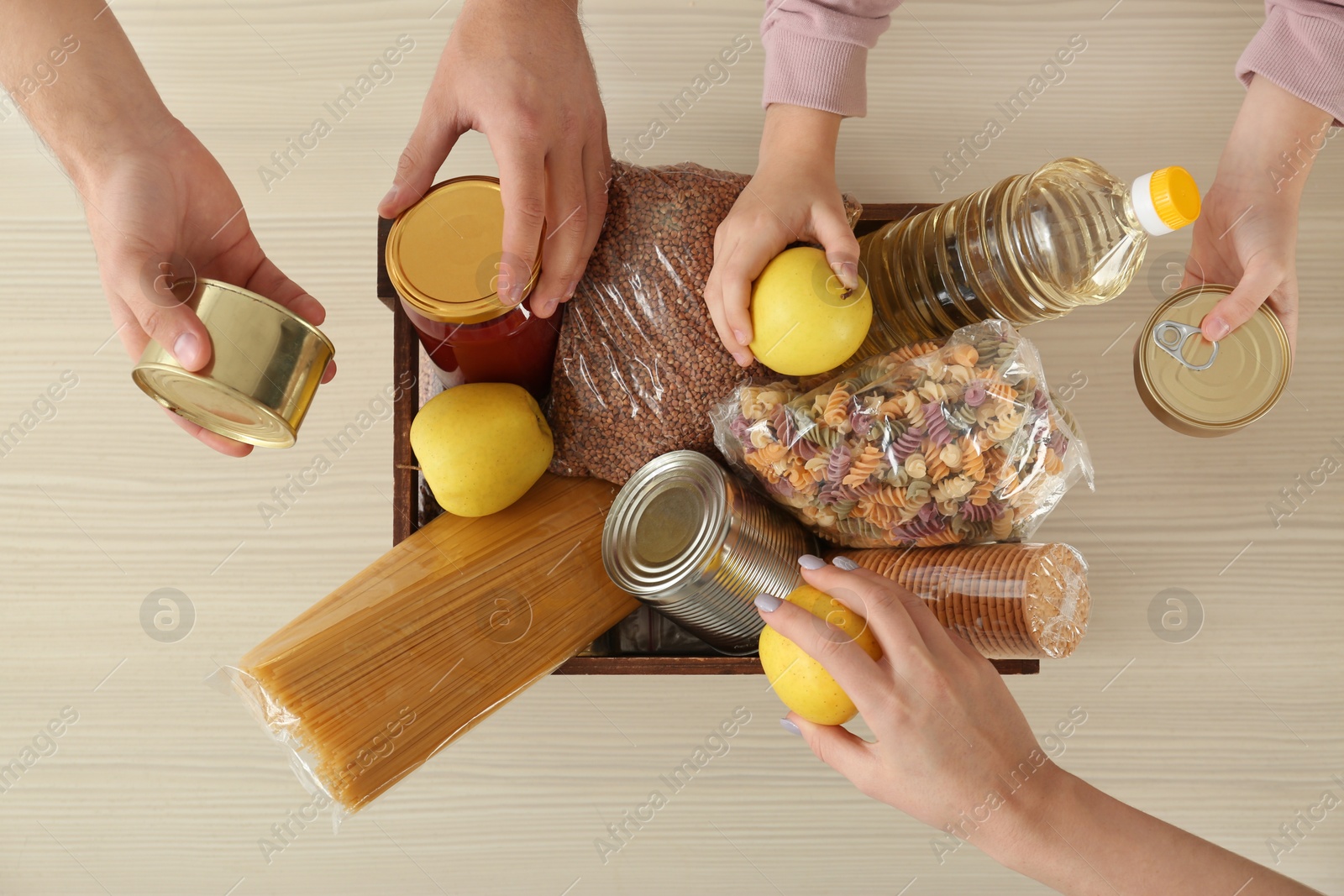 Photo of Volunteers taking food out of donation box on table, top view