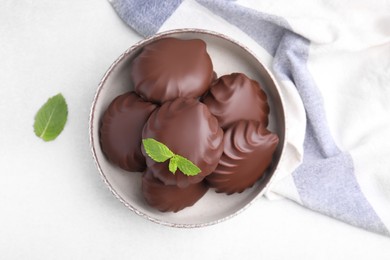 Photo of Delicious chocolate covered zephyrs and mint on white table, flat lay
