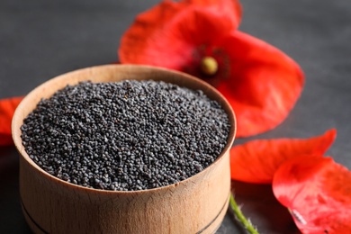 Wooden bowl of poppy seeds and flowers on table, closeup with space for text
