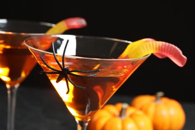 Photo of Decorated glasses with drinks on black background, closeup. Halloween celebration