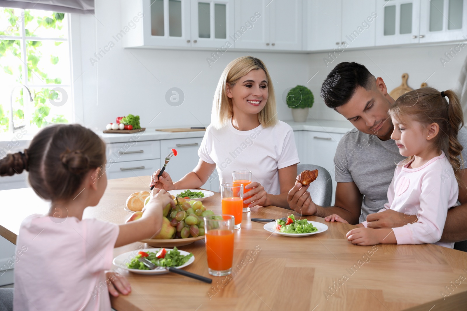 Photo of Happy family having breakfast together at table in modern kitchen