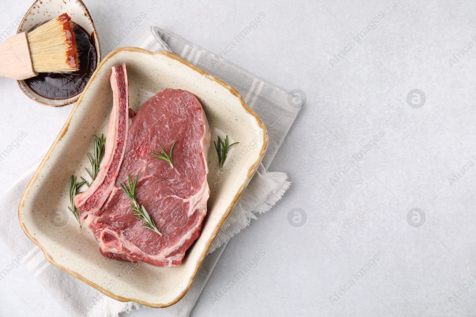 Photo of Raw meat, rosemary and marinade on light table, top view. Space for text