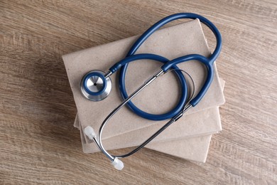Photo of Student textbooks and stethoscope on wooden table, top view. Medical education