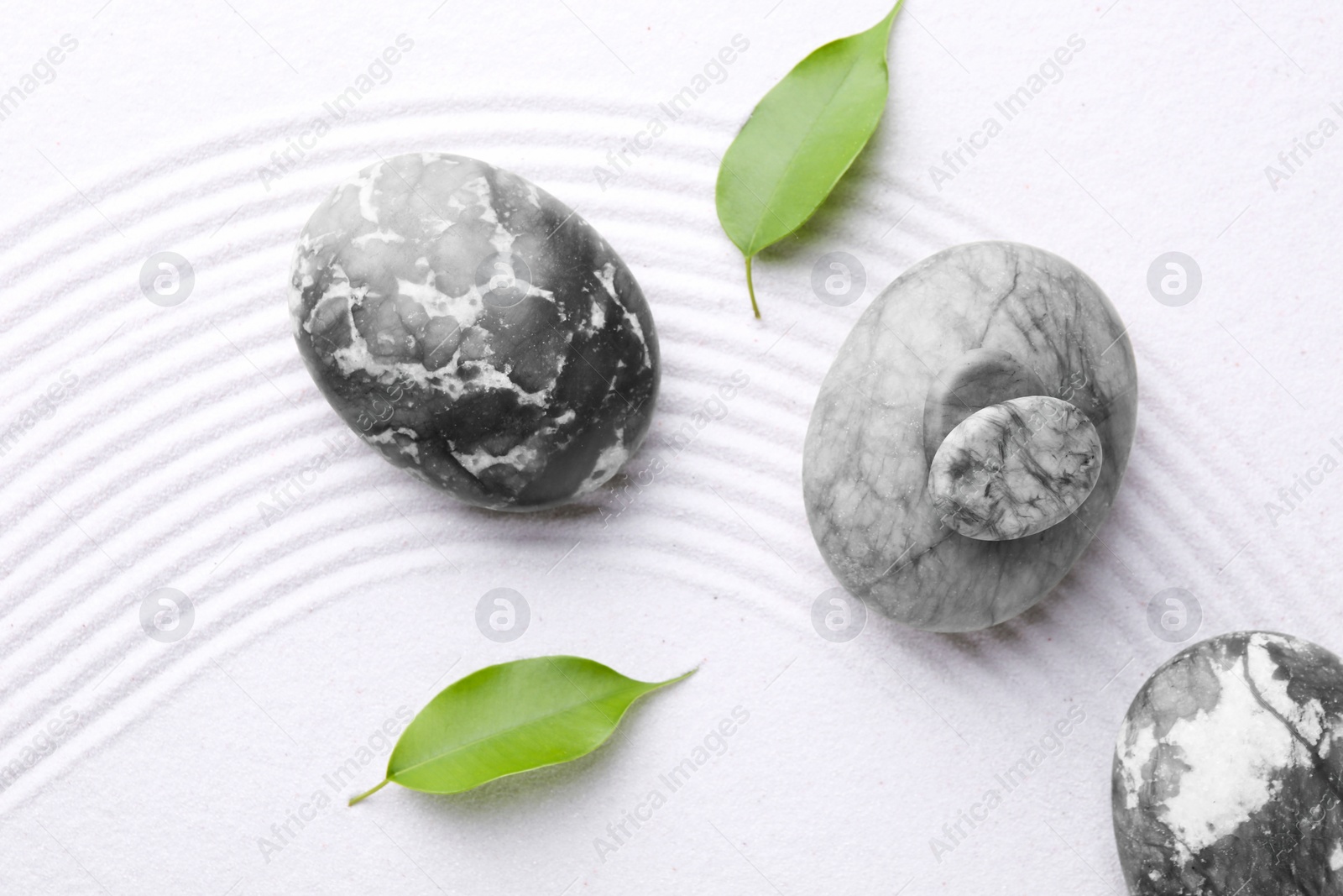 Photo of Zen garden stones and leaves on white sand with pattern, flat lay