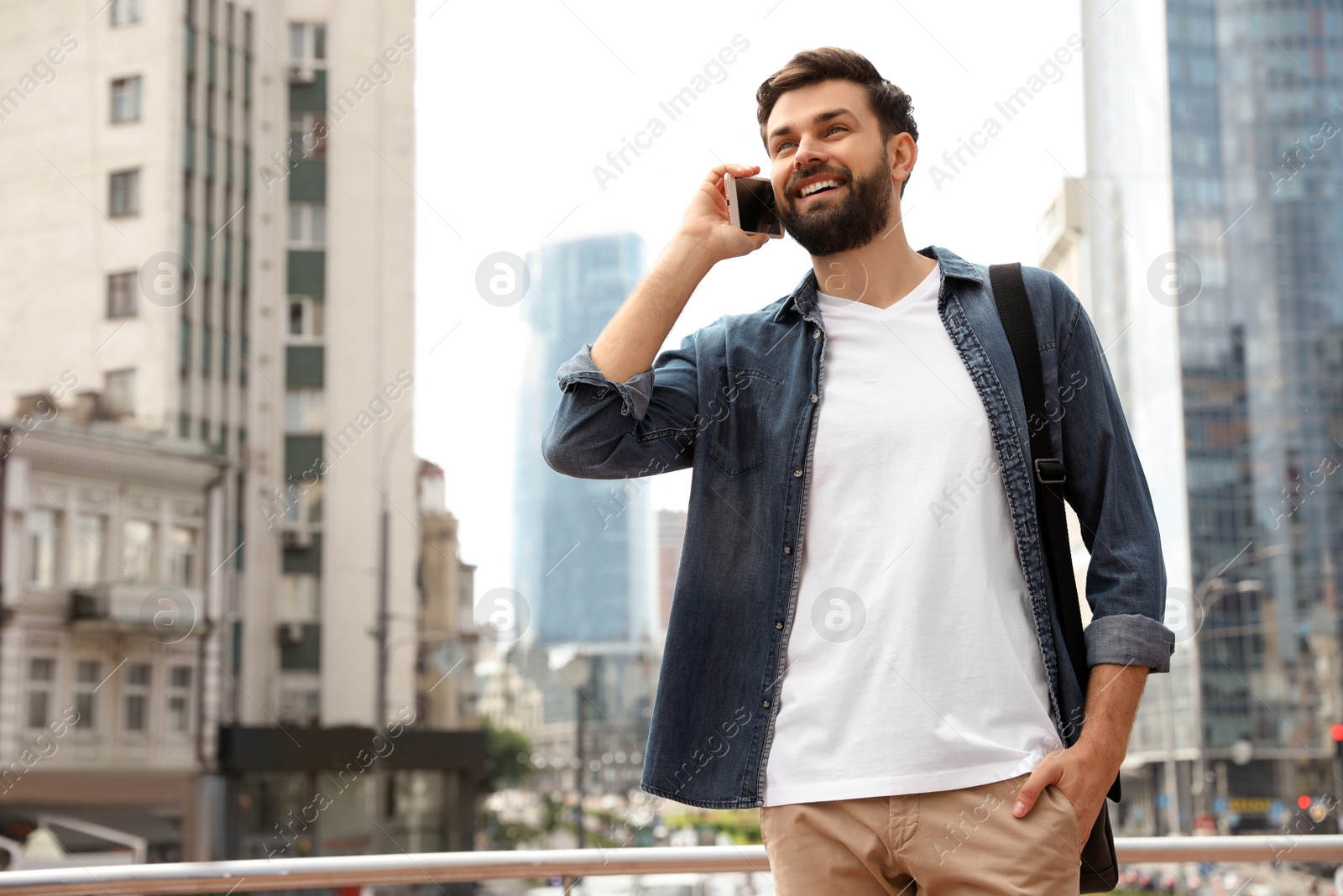 Photo of Handsome man talking on phone in modern city