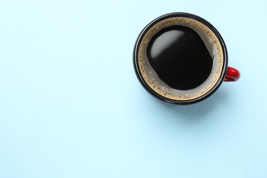 Photo of Aromatic coffee in cup on light blue background, top view. Space for text