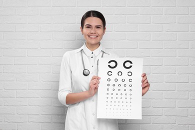 Ophthalmologist with vision test chart near white brick wall