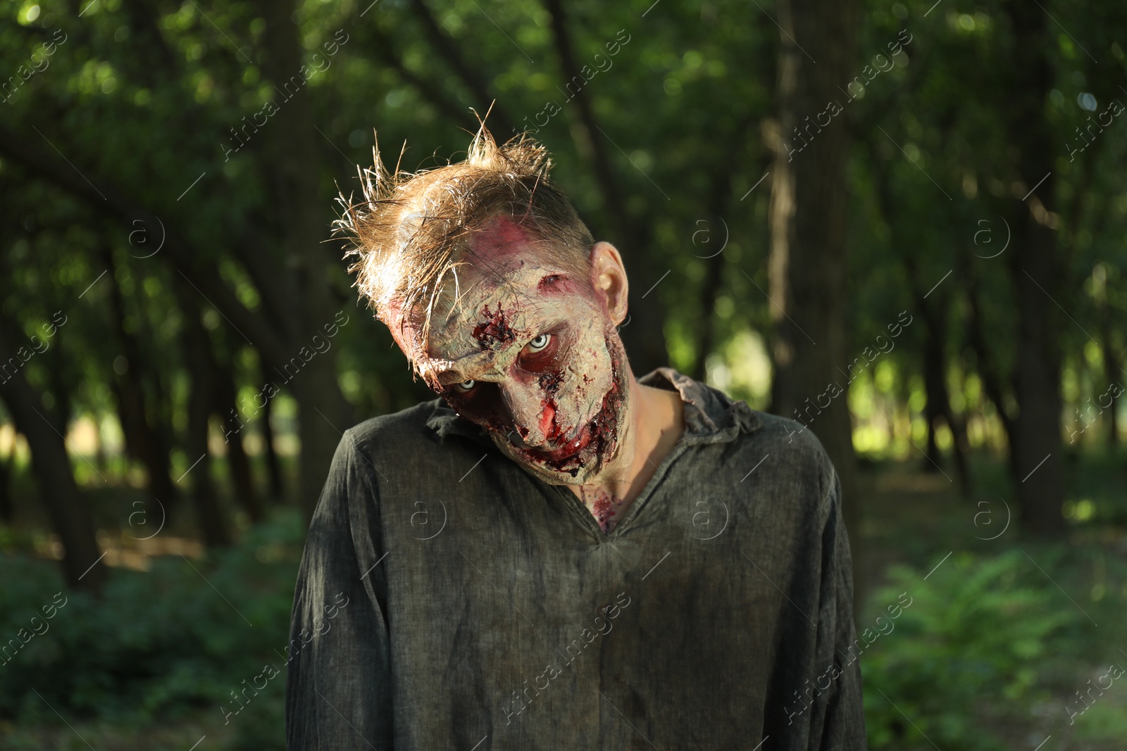 Photo of Scary zombie with bloody face outdoors. Halloween monster