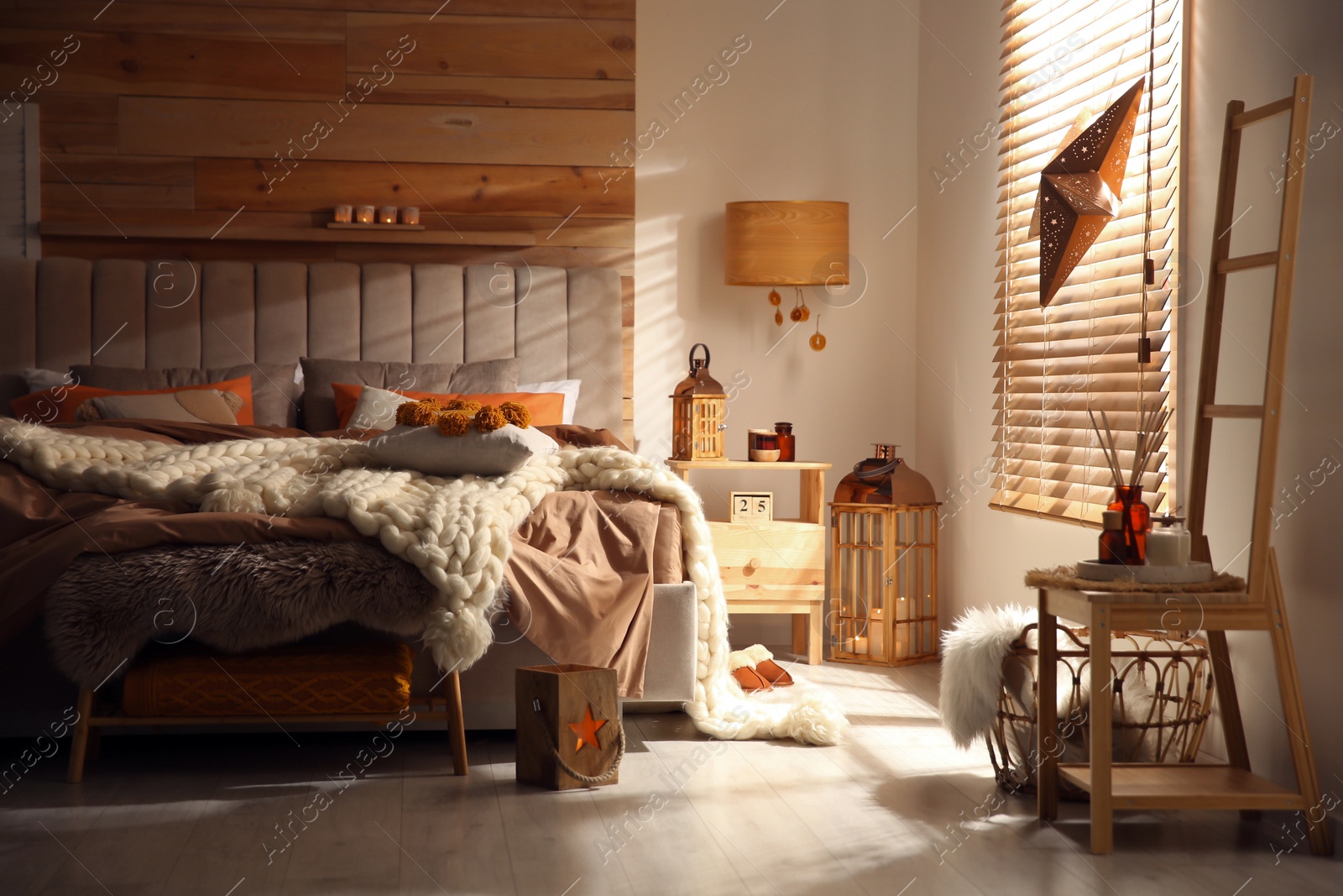 Photo of Cozy bedroom interior with knitted blanket and cushions