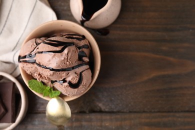 Photo of Bowl of tasty chocolate ice cream served on wooden table, flat lay. Space for text