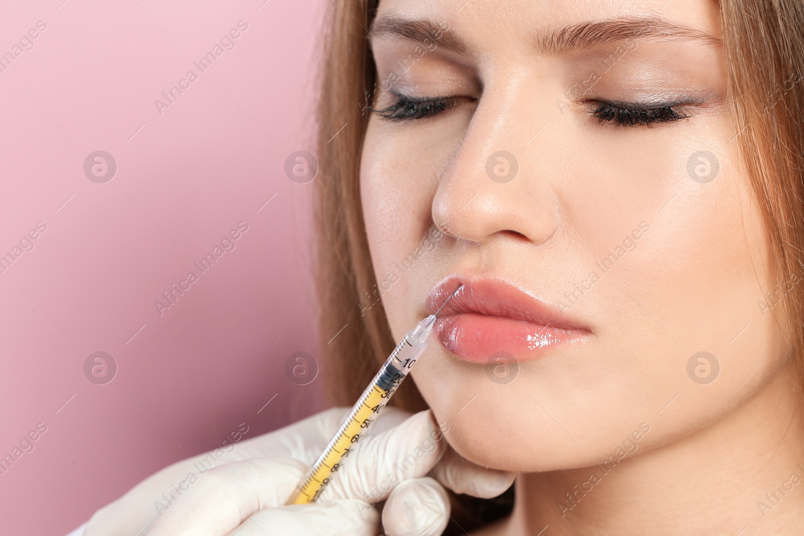 Photo of Young woman getting lips injection on color background, space for text. Cosmetic surgery