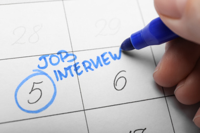 Woman marking date of job interview in calendar, closeup