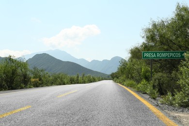 Photo of Picturesque view of big mountains and bushes near road under bright sky