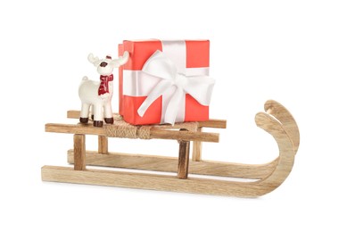 Photo of Wooden sleigh with present and decorative reindeer on white background