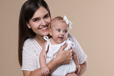 Beautiful mother with her cute baby on beige background