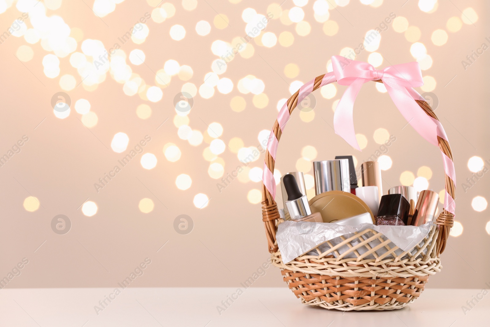 Photo of Wicker basket with cosmetics as present against blurred festive lights. Space for text