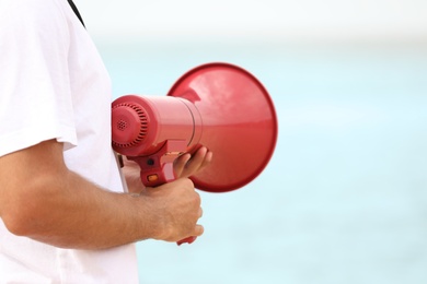 Photo of Male lifeguard with megaphone near sea, closeup