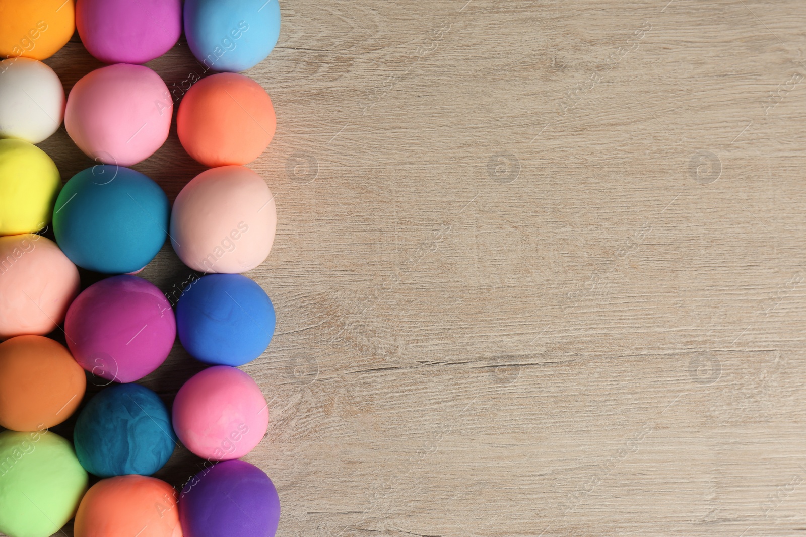 Photo of Different color play dough balls on wooden table, flat lay. Space for text