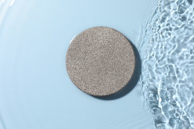 Presentation for product. Stone podium in water on light blue background, top view