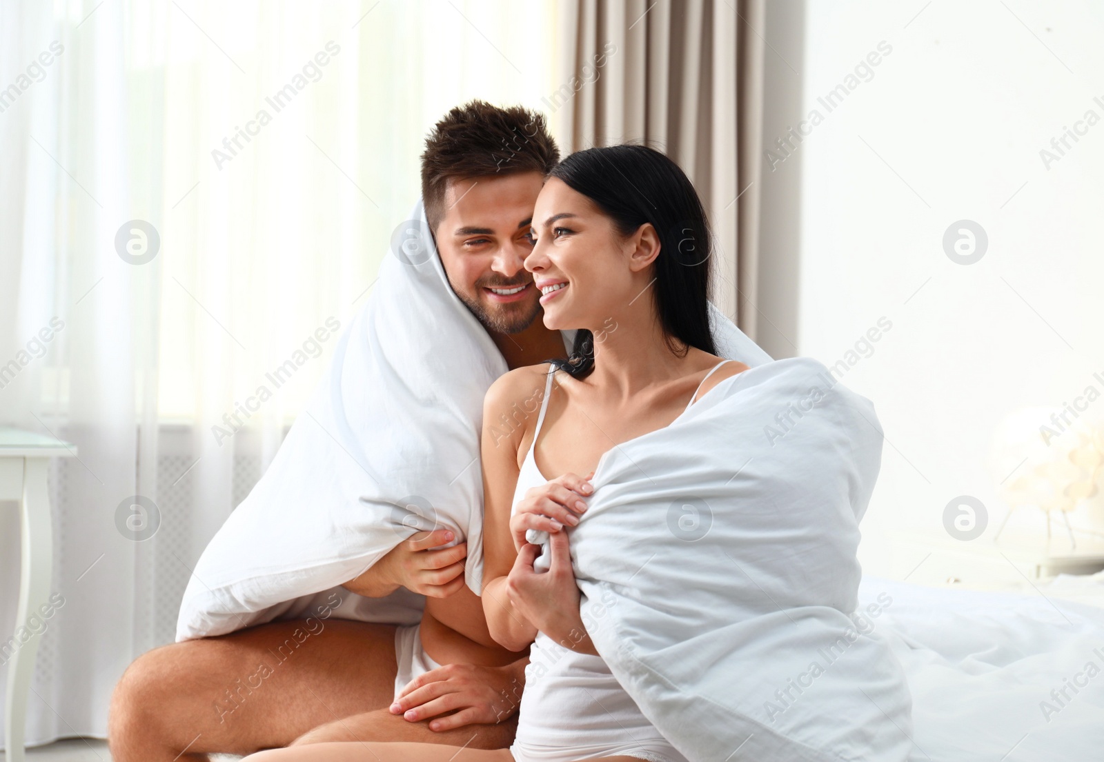 Photo of Young couple in underwear under blanket at home