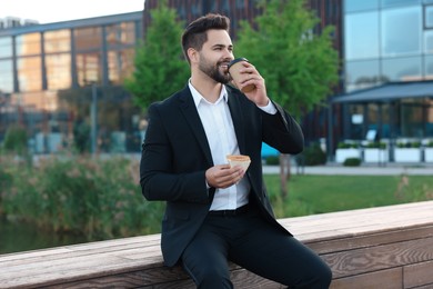 Photo of Smiling young businessman having his lunch outdoors