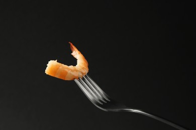 Photo of Fork with tasty shrimp on black background, space for text