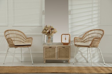 Photo of Living room interior with wooden commode, mirror and wicker chairs