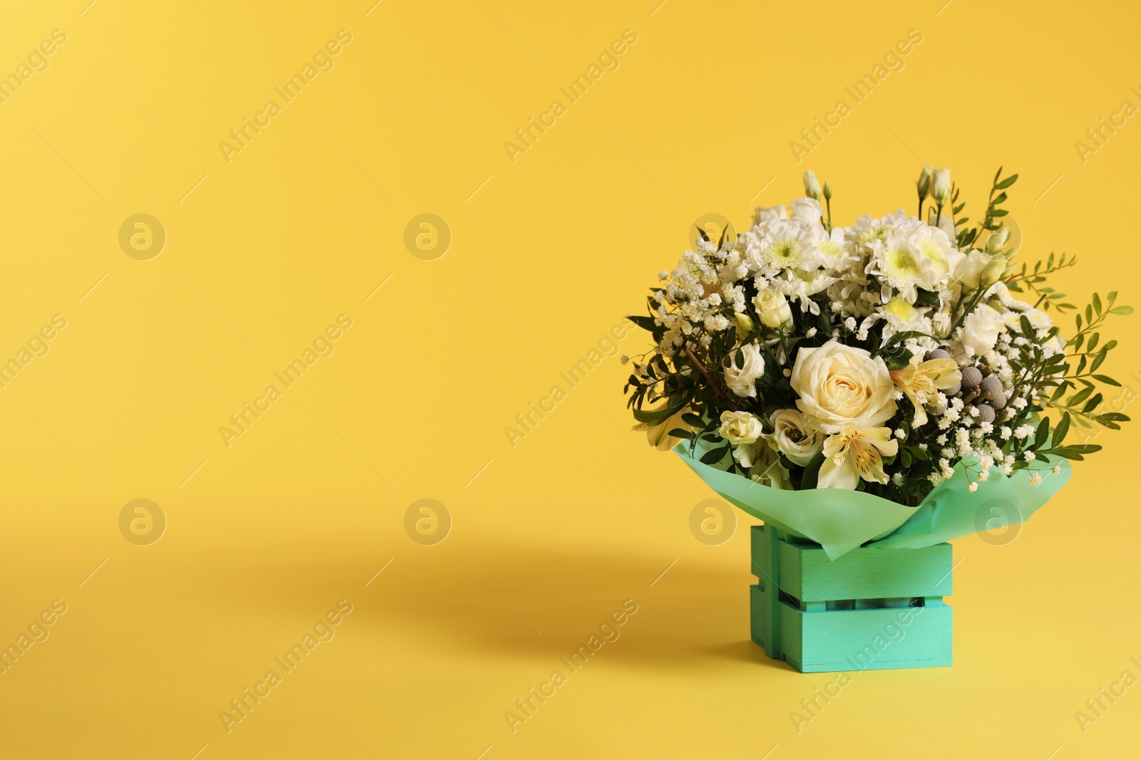 Photo of Beautiful bouquet of flowers in decorative crate on color background. Space for text