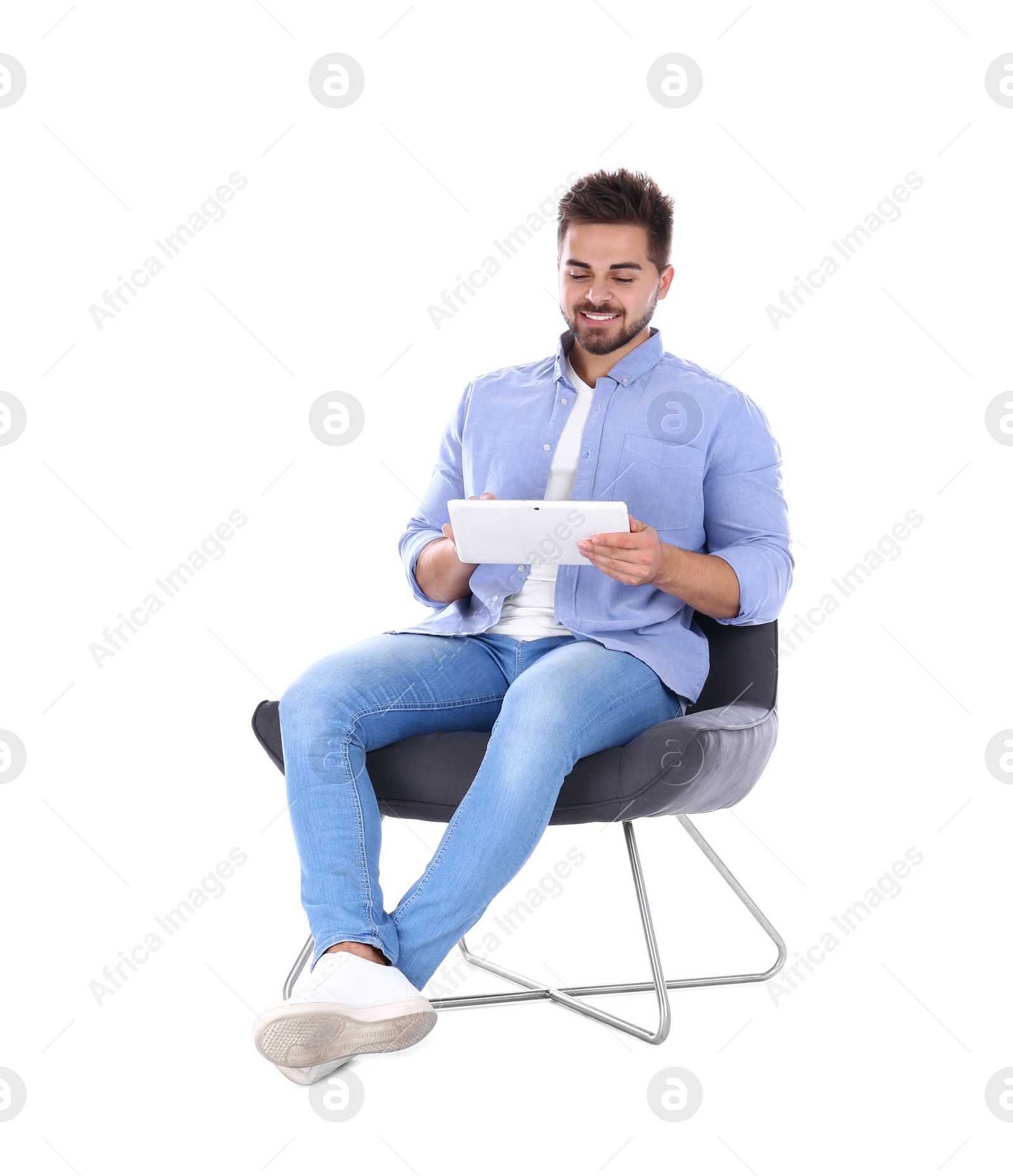 Photo of Young man with tablet sitting in armchair isolated on white