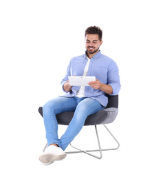 Photo of Young man with tablet sitting in armchair isolated on white