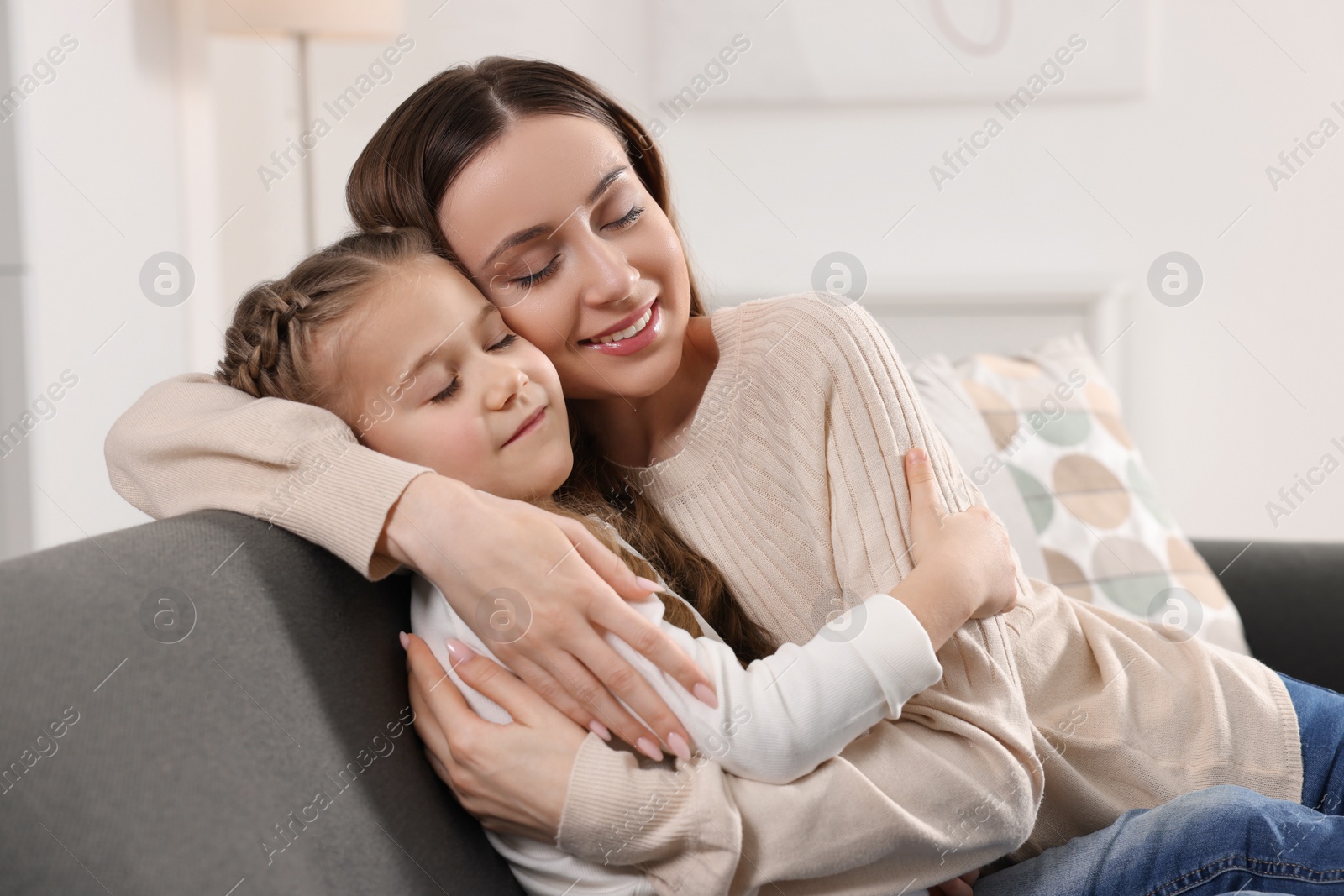 Photo of Happy mother hugging her cute daughter on sofa at home