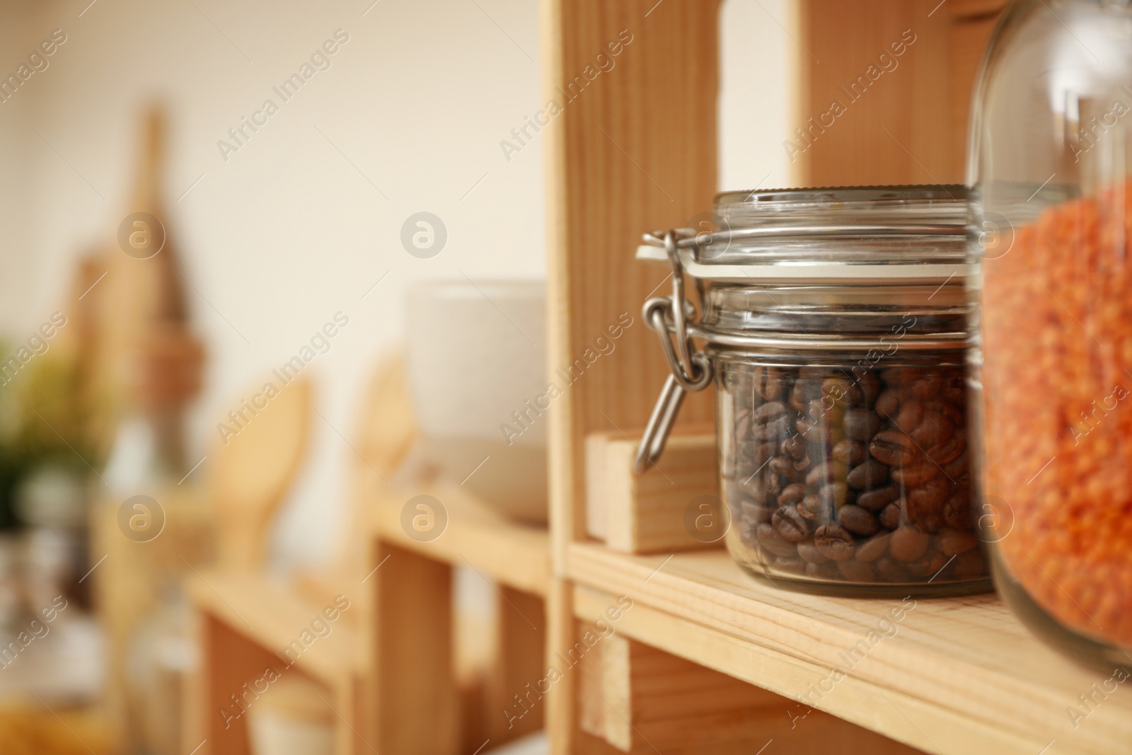 Photo of Glass jar with coffee beans on wooden shelf in kitchen, space for text